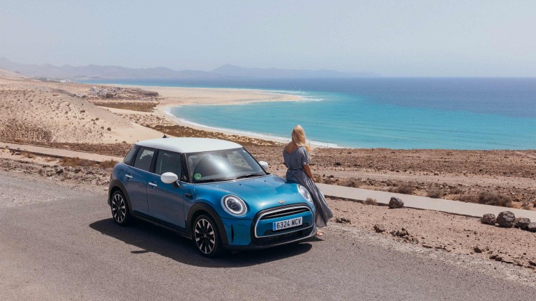 Katarina standing beside her MINI looking at the sea.