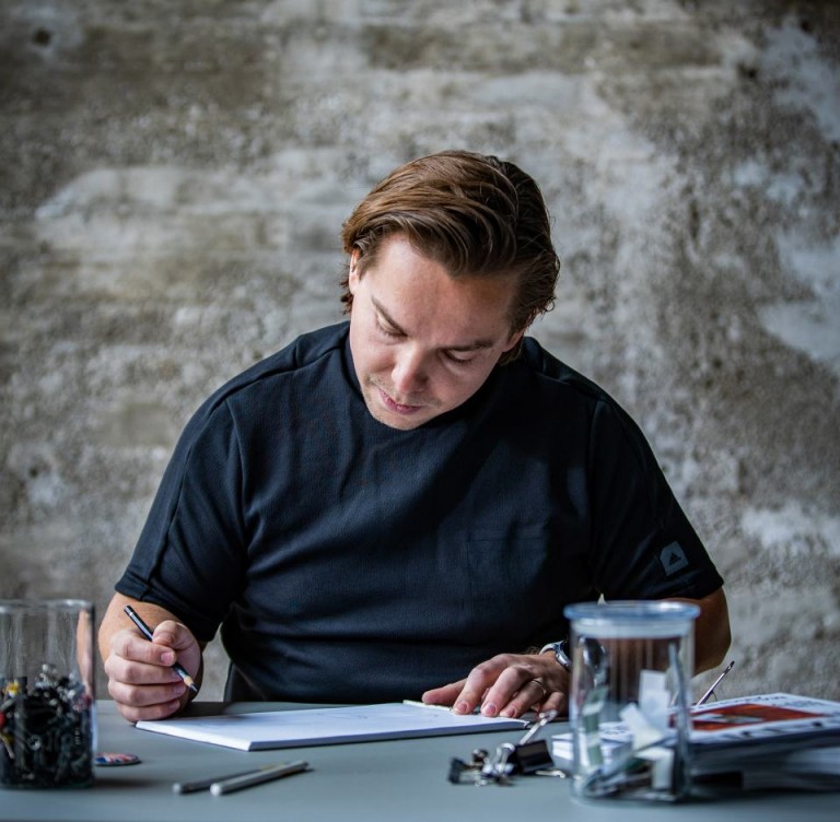 Дизайнер MINI Йозеф Кульманн сидит за столом и рисует MINI. 