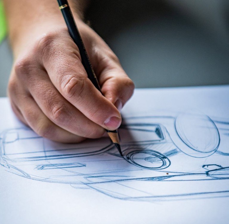 Рука дизайнера MINI Йозефа Кульмана, рисующего детали фар, крупным планом. 